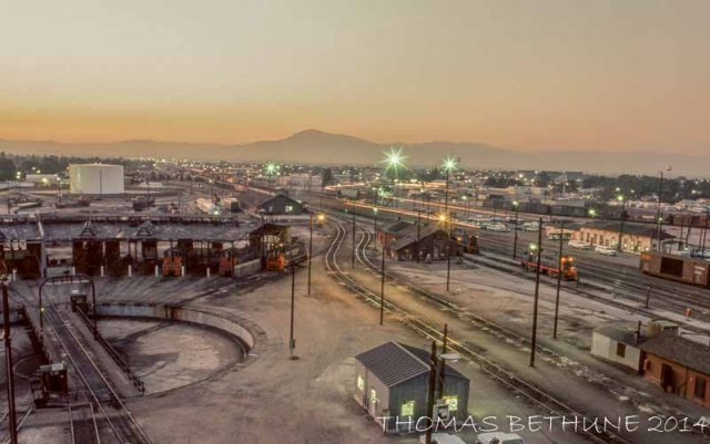 I took this photograph in 1976 in the early morning hours from one of the sand towers at Bakersfield near the completion of a midnight hostler shift. Notice that the water tank is gone from its former location between the roundhouse office in the foreground, and the crew dispatcher/RFE building near the center of the image. Note the Yard Office and switchman's shanty at about the three o'clock position. Behind that are the Santa Fe transfer tracks. The two locomotives at the crew dispatcher's office are yard engines while the locomotive adjacent to the roundhouse is for a local (all yard engines faced west at Bakersfield).